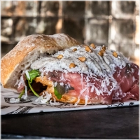 Dungesneden ossenhaas met rucola, geroosterde pijnboompitten, verse Parmezaanse kaas, peper, zout, huisgemaakte truffelmayonaise en of pestomayonaise. <br>Luxe op z'n best. 