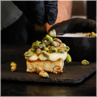 Onze heerlijke fluffy blondie brownie met een topping van witte chocoladesaus en gebrande pistachenoten. <br><br><i>Every bite needs to be perfect!</i>