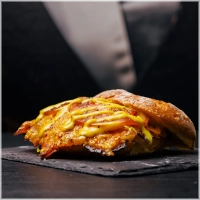 Onze signature beenham.<br>Door de chef gebraden met rozemarijn, knoflook & tijm, <br>Daarna flinterdun gesneden en super juicy, met gesmolten cheddar, ijsbergsla, vleestomaat en onze honing-mosterdsaus.