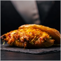Malse geplukte kippendijen gemarineerd in onze chilisaus met gesmolten cheddar en frisse ijsbergsla.<br><br>Durf jij 'm heter te maken? Kies dan voor extra sambal.